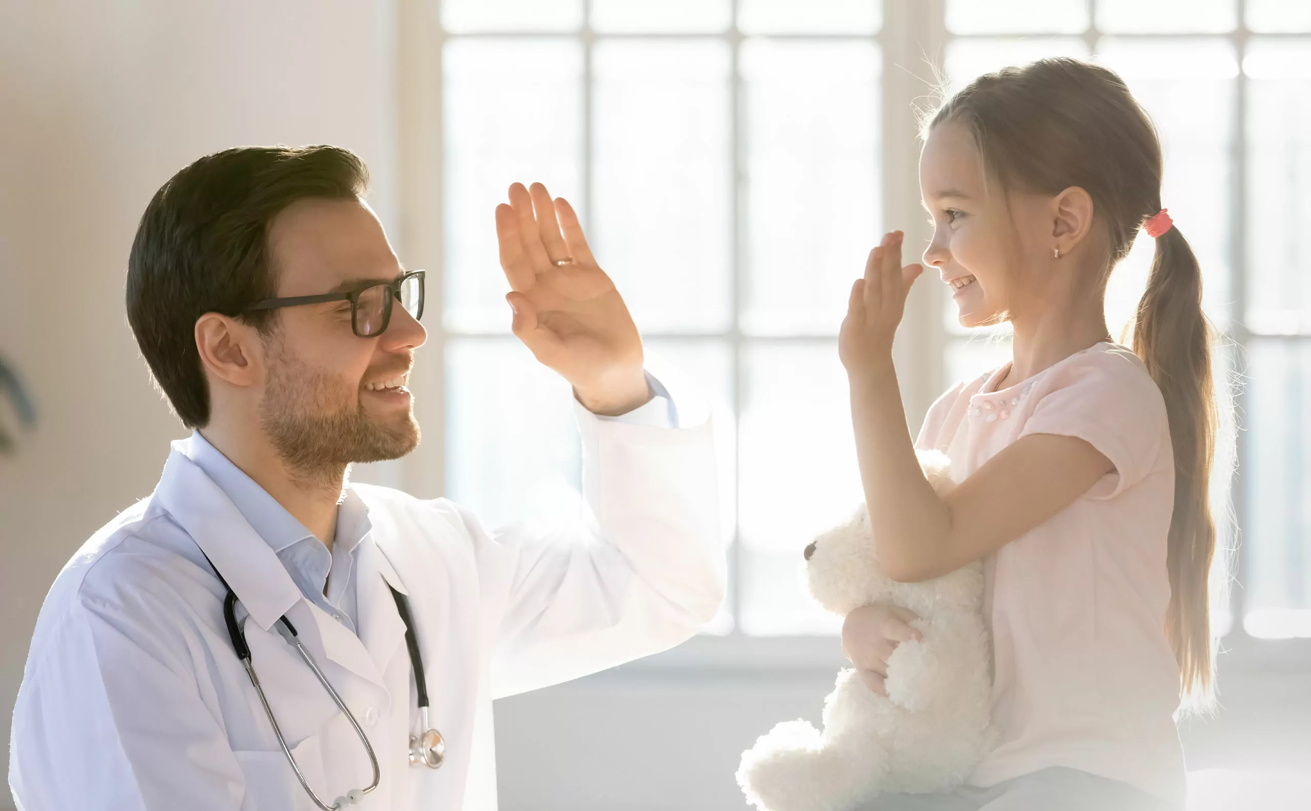 Pediatra saludando a una niña durante una consulta